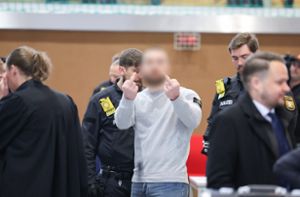 Ein Angeklagter zeigt beim Prozessauftakt in Bamberg zwei Mittelfinger. Foto: Daniel Löb/dpa
