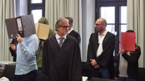Ein wegen Doppelmordes angeklagter Mann (Zweiter von links) und seine ebenfalls angeklagte Frau (rechts), stehen hinter einem der Beihilfe angeklagten Mann aus Albstadt-Pfeffingen (links) in der Anklagebank im Landgericht. Foto: dpa/Karl-Josef Hildenbrand